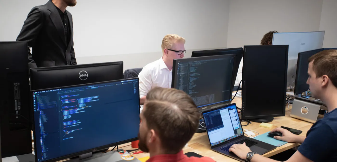 A development team reviewing code across several monitors
